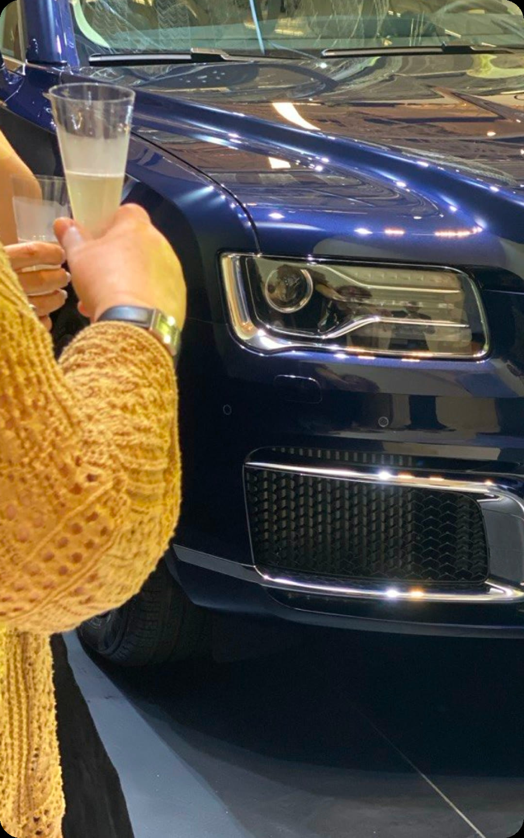A guest with a glass next to an AURUS car at the presentation